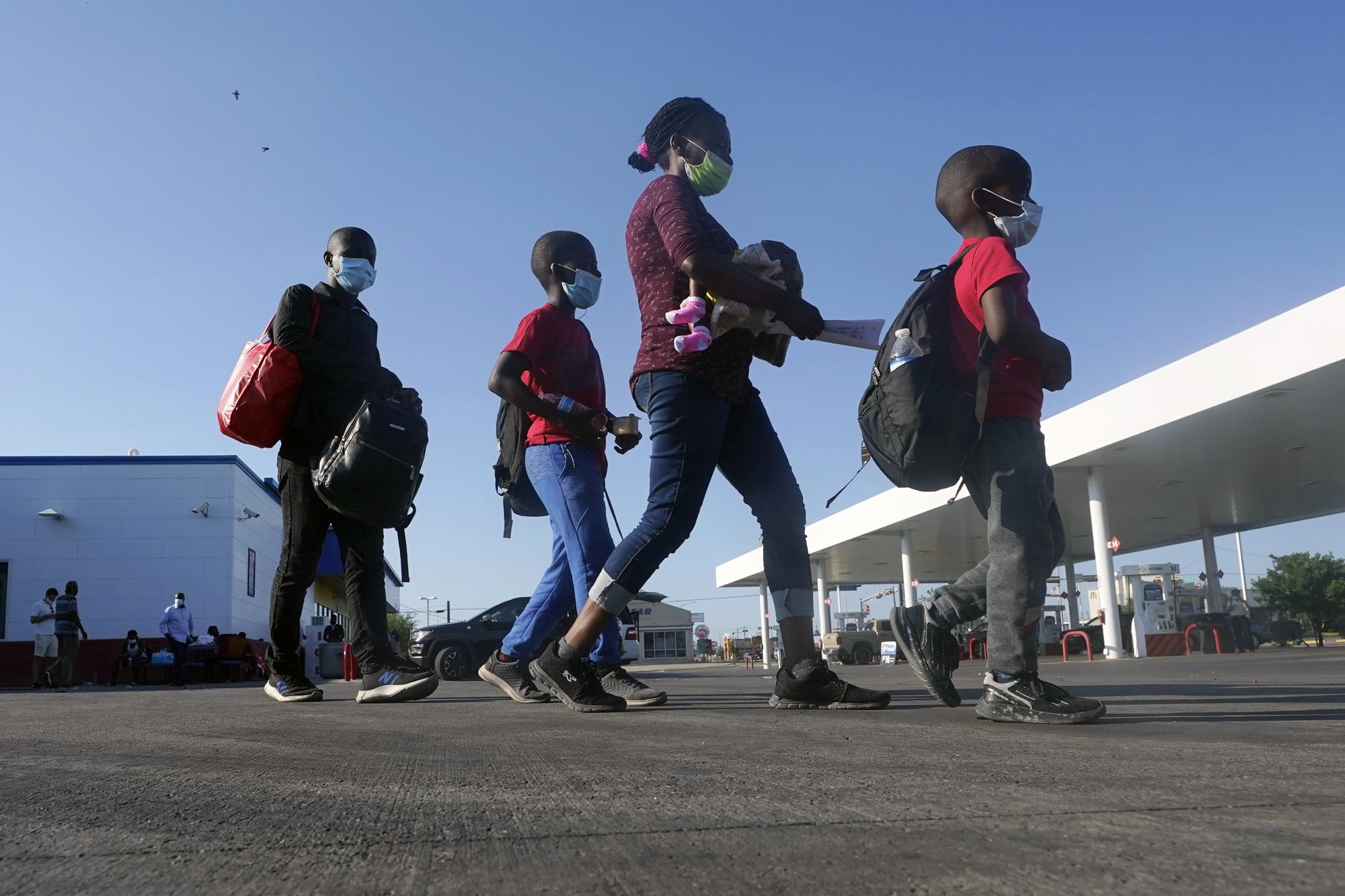 FILE - Haitian migrants walk to a bus after they were processed and released after spending time at a makeshift camp near the International Bridge, Sept. 19, 2021, in Del Rio, Texas. Biden and senior officials talked tough — "Do not come," Vice President Kamala Harris warned on a June visit to Guatemala, repeating herself for emphasis — but migrants who kept coming spoke of the change in presidential administrations and stories from friends and relatives who were quickly released in the United States. (AP Photo/Eric Gay, File)