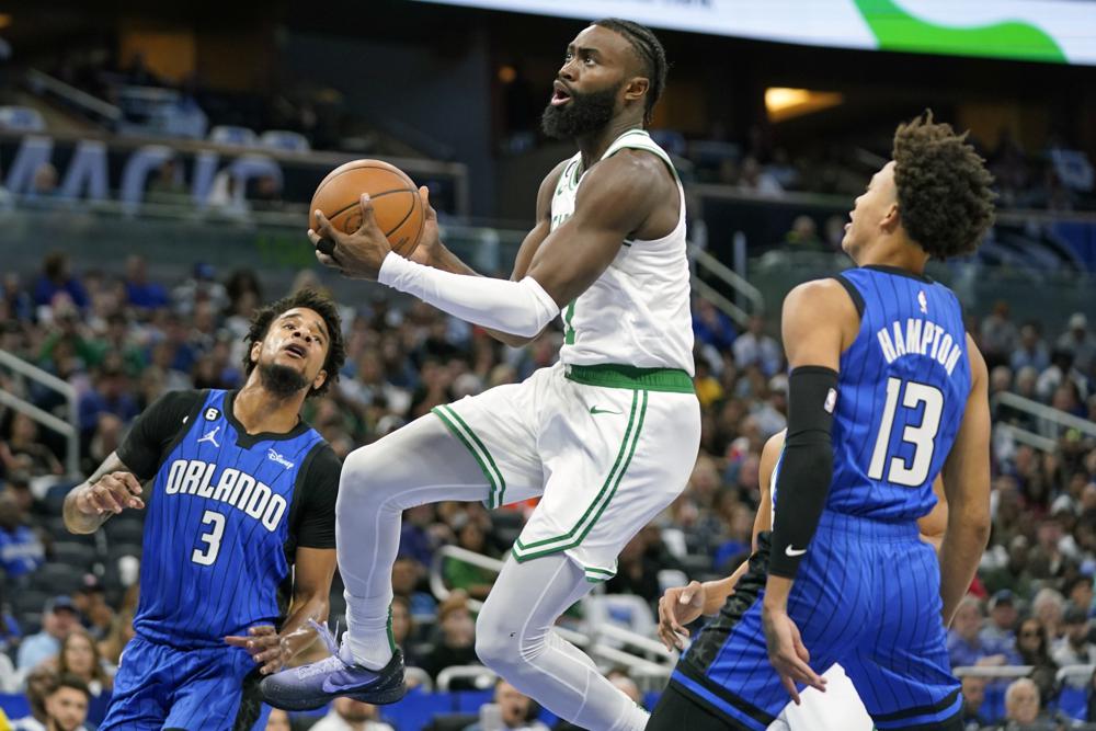 Boston Celtics' Jaylen Brown, center, shoots as he gets between Orlando Magic's Chuma Okeke (3) and R.J. Hampton (13) during the first half of an NBA basketball game, Saturday, Oct. 22, 2022, in Orlando, Fla. (AP Photo/John Raoux)