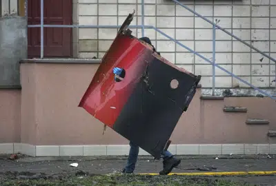 Un hombre lleva un fragmento del helicóptero que cayó en un jardín de infantes en Brovary, en las afueras de Kiev, Ucrania, miércoles 18 de enero de 2023. (AP Foto/Efrem Lukatsky)