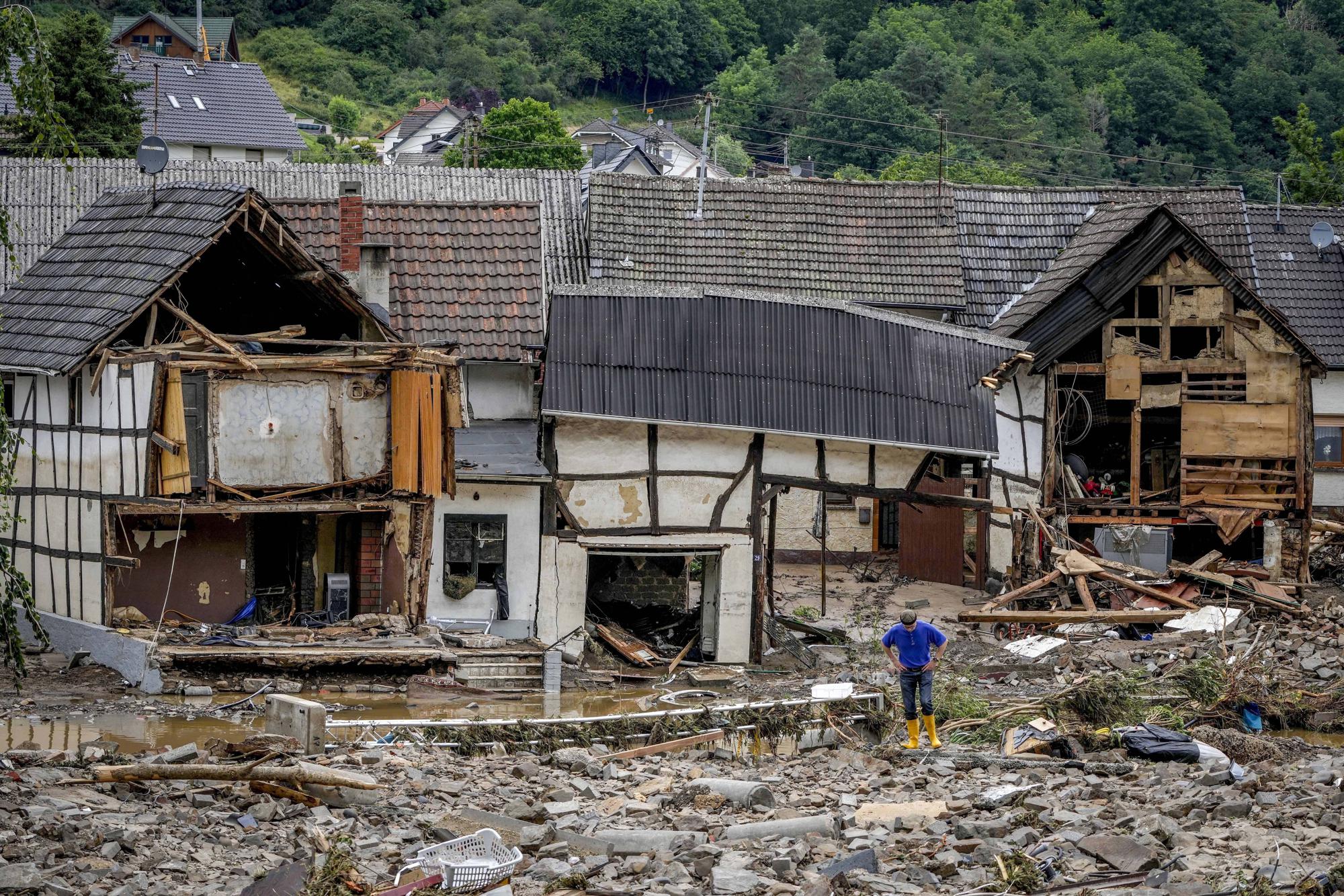 FILE - A man stands in front of destroyed houses close to the Ahr river in Schuld, Germany, July 15, 2021. Due to heavy rain falls the Ahr river dramatically went over the banks the evening before. (AP Photo/Michael Probst, File)