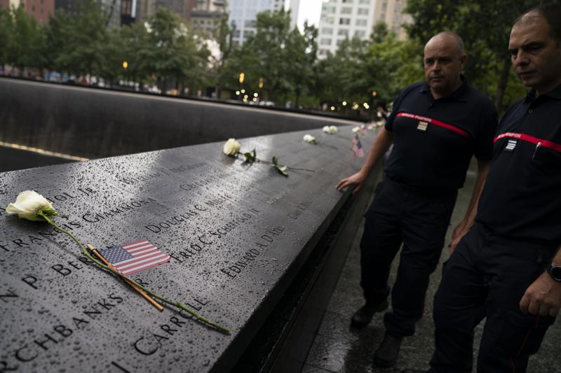 Visitors browse the south pool as flowers and American flags rest among the names of the fallen at the National September 11 Memorial & Museum, Thursday, Sept. 9, 2021, in New York. (AP Photo/John Minchillo)