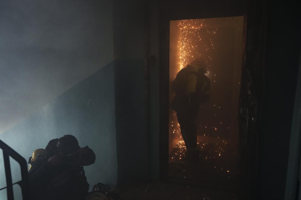 A firefighter opens the door of a burning apartment after a Russian bombardment in Kharkiv, Ukraine, Thursday, April 21, 2022. (AP Photo/Felipe Dana)