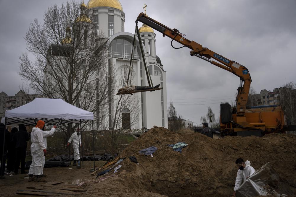 Una grúa levanta un cadáver de una fosa común con el fin de que sea trasladado a una morgue para su identificación, el domingo 10 de abril de 2022, en Bucha, a las afueras de Kiev, Ucrania. (AP Foto/Rodrigo Abd)