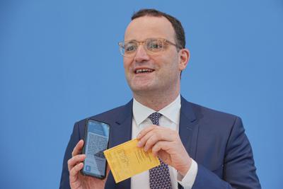 El ministro de Salud de Alemania, Jens Spahn, presenta la aplicación Corona Warn con un certificado digital de vacunación en la pantalla de su celular y su propio certificado de vacunación en la mano, durante una conferencia de prensa sobre la situación por el coronavirus, en Berlín, Alemania, el jueves 10 de junio de 2021. (Michael Kappeler/dpa vía AP)