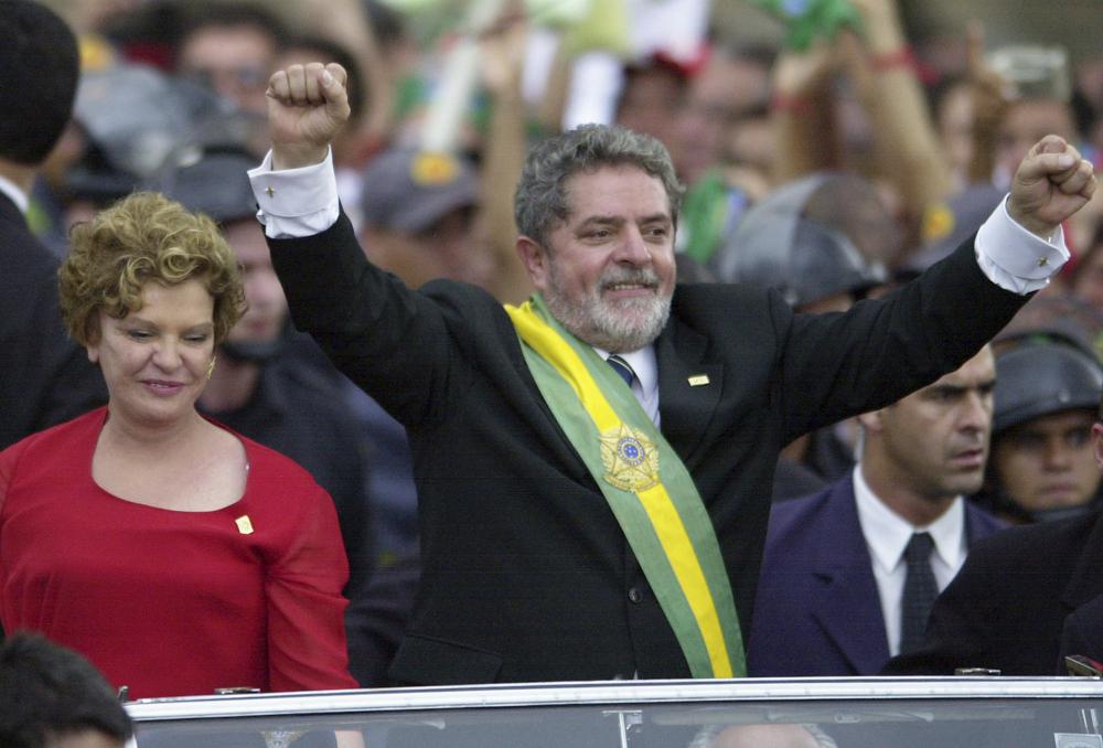 ARCHIVO - El presidente de Brasil, Luiz Inácio Lula da Silva, levanta los brazos mientras viaja en un automóvil abierto con su esposa Marisa, luego de prestar juramento como nuevo presidente del país, en Brasilia, Brasil, el 1 de enero de 2003. (Foto AP/ Víctor R. Caivano, Archivo)