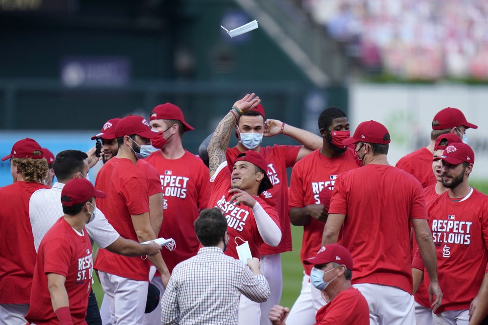 Kolten Wong de los Cardenales de San Luis lanza una mascarilla al aire mientras celebra con sus compañeros de equipo después de derrotar a los Cerveceros de Milwaukee en un juego de béisbol para ganar un nacimiento en los playoffs el domingo 27 de septiembre de 2020 en San Luis.