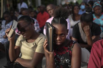 Feligreses durante una misa realizada en el terreno junto a una iglesia que resultó dañada por un sismo en Les Cayes, Haití, el domingo 22 de agosto de 2021, ocho días después de que un terremoto de magnitud 7,2 sacudió la zona. (AP Foto/Matias Delacroix)