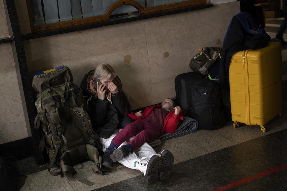 A woman with her daughter waits for a train as they try to leave Kyiv, Ukraine, Thursday, Feb. 24, 2022. Russian troops have launched their anticipated attack on Ukraine. Big explosions were heard before dawn in Kyiv, Kharkiv and Odesa as world leaders decried the start of an Russian invasion that could cause massive casualties and topple Ukraine's democratically elected government. (AP Photo/Emilio Morenatti)