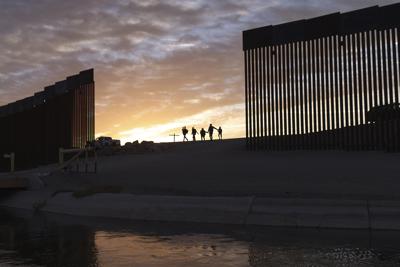 ARCHIVO - En esta fotografía de archivo del jueves 10 de junio de 2021, un par de familias de inmigrantes brasileños cruzan por una brecha en el muro fronterizo para ingresar a Yuma, Arizona, desde México con el fin de solicitar asilo. (AP Foto/Eugene Garcia, archivo)