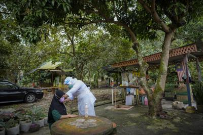 ARCHIVO - Una enfermera malasia pone la vacuna de Sinovac contra el COVID-19 a una anciana en su casa de Sabab Bernam, en el estado central de Selangor, Malasia, el 13 de julio de 2021. Cuando Camboya empezó a vacunar contra el COVID-19, las filas se extendían por calles enteras y la gente dejaba los zapatos en su puesto para guardar el sitio mientras se cubrían del sol. Pero tres meses más tarde, apenas el 11% de la población había recibido al menos una dosis. En Japón, un país mucho más rico, hicieron falta dos semanas más para llegar a esa cifra. (AP Foto/Vincent Thian, Archivo)