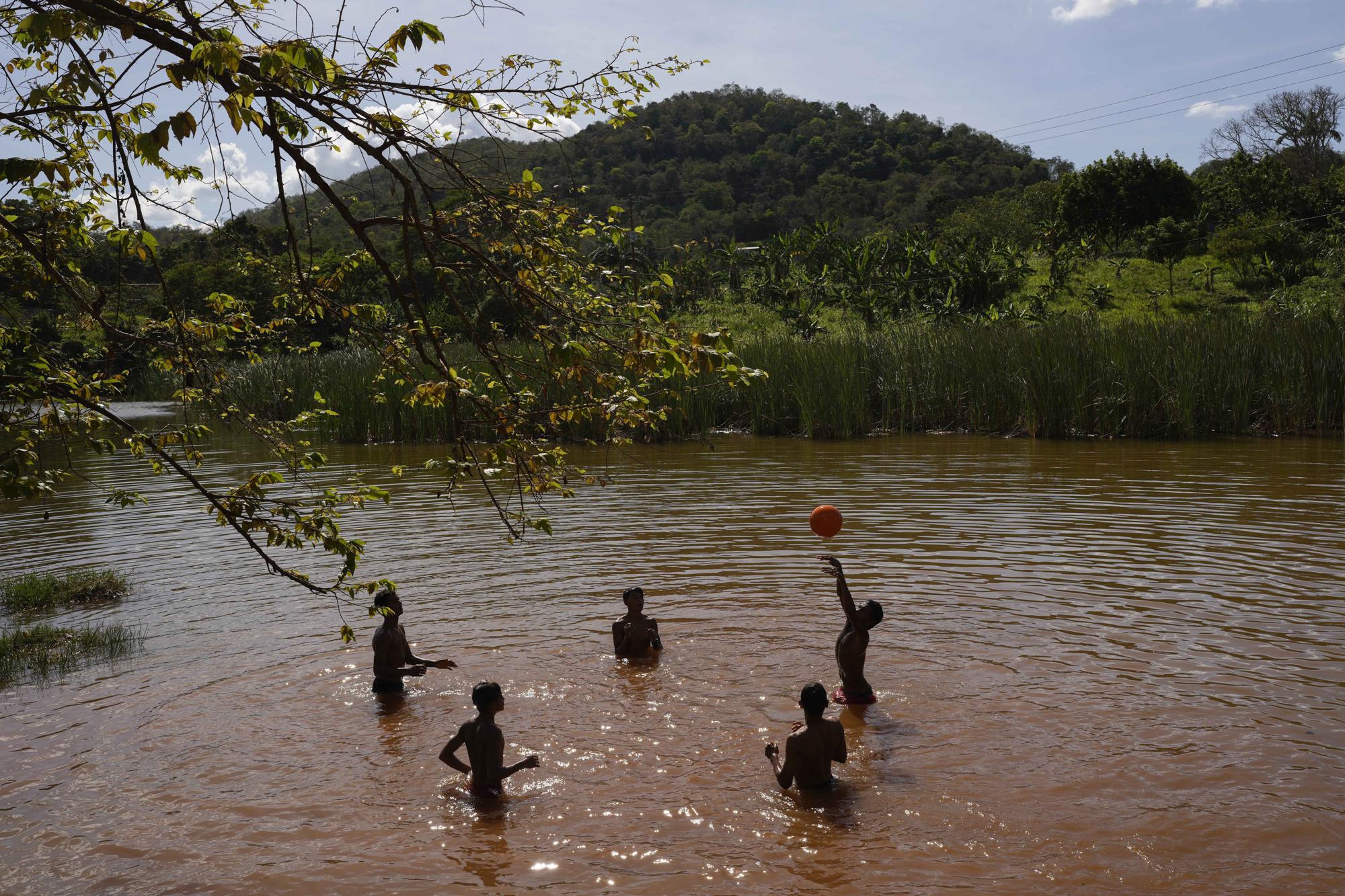 Los familiares de los mineros de oro juegan a la pelota en un estanque junto a una mina en El Callao, Venezuela, el viernes 28 de abril de 2023. (Foto AP/Matias Delacroix)