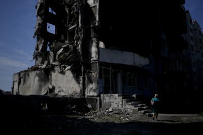 Una mujer camina junto a un edificio destruido por los bombardeos rusos en Borodyanka, en las afueras de Kiev, Ucrania, el martes 21 de junio de 2022. (AP Foto/Natacha Pisarenko)