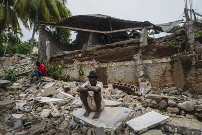 ARCHIVO - En imagen de archivo del 17 de agosto de 2021, un hombre se encuentra sentado en los escombros de un hospital destruido por un sismo de magnitud 7,2 en Fleurant, Haití. (AP Foto/Fernando Llano, archivo)