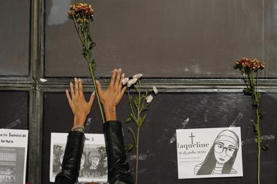 Una mujer coloca flores en la fachada de la Fiscalía General de la República durante una protesta por la desaparición de Debanhi Escobar y otras mujeres, el viernes 22 de abril de 2022, en la Ciudad de México. (AP Foto/Eduardo Verdugo)