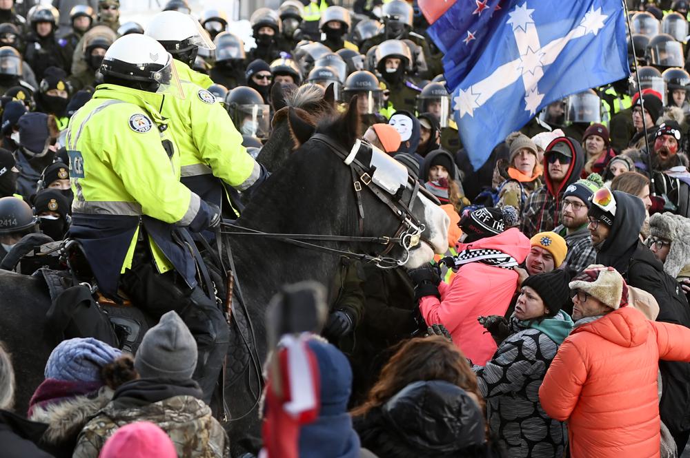 Protesters react as Toronto Police mounted unit move in to disperse them as police take action to put an end to a protest, which started in opposition to mandatory COVID-19 vaccine mandates and grew into a broader anti-government demonstration and occupation, Friday, Feb. 18, 2022, in Ottawa. (Justin Tang/The Canadian Press via AP)