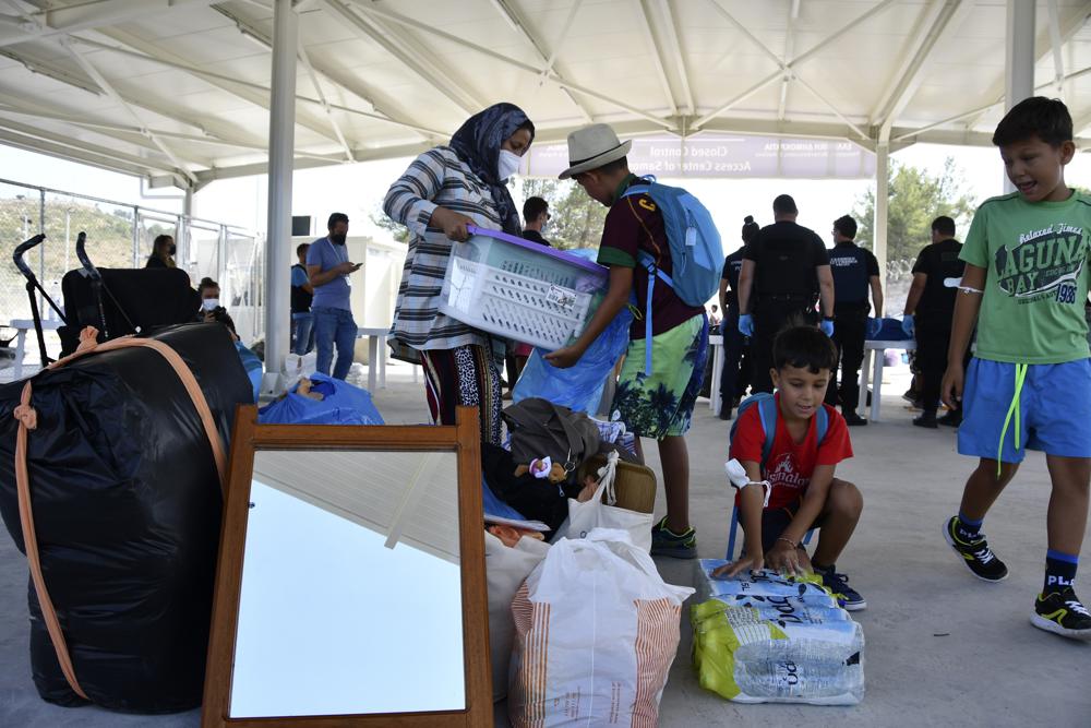 Migrants with their belongings arrive at the new closed monitored facility in Zervou village, on the eastern Aegean island of Samos, Greece, Monday, Sept. 20, 2021. The transfer of the migrants to the new, €43 million ($50 million) facility began Monday and be completed by Wednesday. (AP Photo/Michael Svarnias)