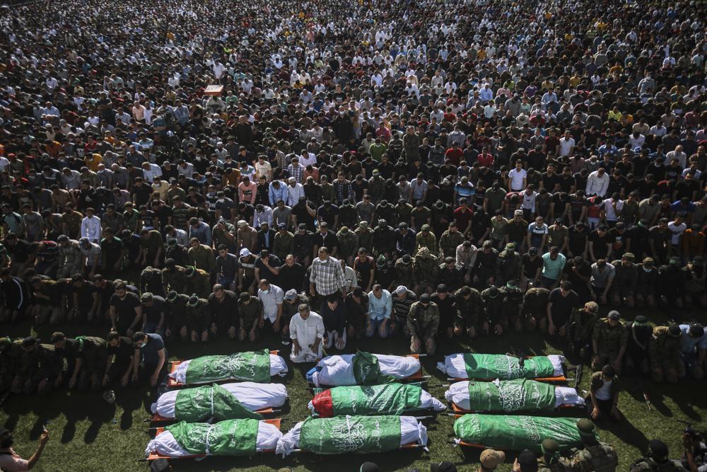 Palestinians pray by the bodies of members of the Izzedine al-Qassam Brigades, the military wing of Hamas movement, who died in Israeli bombardment of a tunnel, during their funeral in Khan Younis, southern Gaza Strip, Friday, May 21, 2021. A cease-fire took effect early Friday after 11 days of heavy fighting between Israel and Gaza's militant Hamas rulers that was ignited by protests and clashes in Jerusalem. (AP Photo/Yousef Masoud)