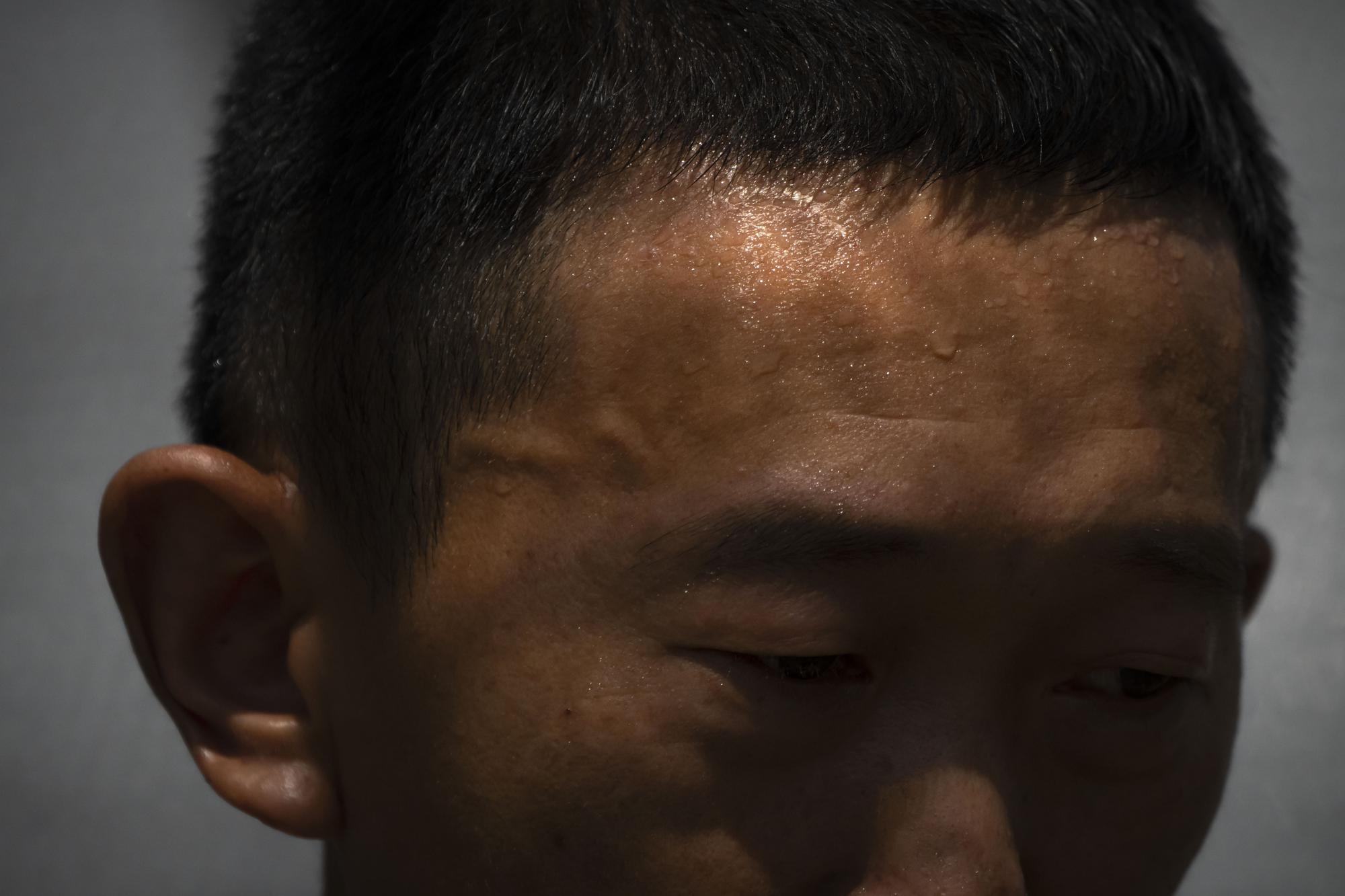 FILE - Sweat forms on the forehead of Gan Bingdong as he stands amid vegetable plots on a hot day at his farm in Longquan village in southwestern China's Chongqing Municipality, Saturday, Aug. 20, 2022. The very landscape of Chongqing, a megacity on the Yangtze River, has been transformed by China's worst heat wave since modern record-keeping began six decades ago, and an accompanying drought. (AP Photo/Mark Schiefelbein, File)