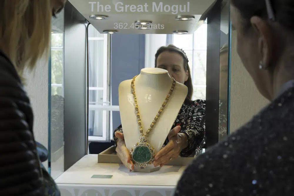 An employee of Christie's displays the Great Mogul Emerald and Diamond Necklace by Harry Winston, estimated between 450,000 - 640,000 CHF (Swiss Francs), in display case, during the preview of "The World of Heidi Horten" the 700 piece jewellery collection of the late Austrian billionaire Heidi Horten, at Christie's Auction House in Geneva, Switzerland, Monday, May 8, 2023. (Salvatore Di Nolfi/Keystone via AP)