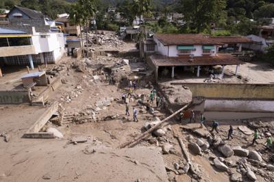 Personas caminan entre casas dañadas por inundaciones en El Castaño, Venezuela, el martes 18 de octubre de 2022. (AP Foto/Juan Pablo Arraez)