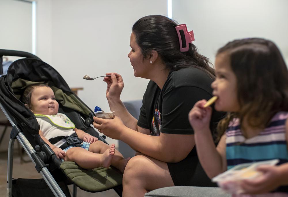 Venezuelan asylum-seeker Oriana Marcano feeds her children Adonai, 8-months, and Amaloha, 3, in El Paso, Texas, Friday, May 12, 2023. When the family was lost in Panama's Darien Gap last year, her husband, Luis Lopez, often knelt in the mud to beg God not to abandon them. Now safe in El Paso after fleeing Venezuela and hosted by a Catholic bishop, the family awaits his sister and mother who also fled the country and crossed through the jungle, but with the end of U.S. pandemic-era asylum regulations and new migration rules looming over them. (AP Photo/Andres Leighton)