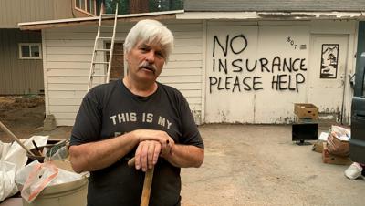 Tod Johnson de pie ante su casa de South Lake Tahoe, California, el martes 31 de agosto de 2021, al día siguiente de que se ordenara evacuar la ciudad por el incendio Caldor. Ha escrito "Sin seguro, por favor ayuden" sobre su casa, que no está asegurada, con la esperanza de que los bomberos ayuden a salvarla si el fuego llega a su vecindario. (AP Foto/Terry Chea)