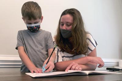 Emily Goss acompaña a su hijo de 5 años a hacer la tarea en la cocina de su casa en Monroe, Carolina del Norte, el lunes 13 de septiembre de 2021. (Foto AP/Sarah Blake Morgan)