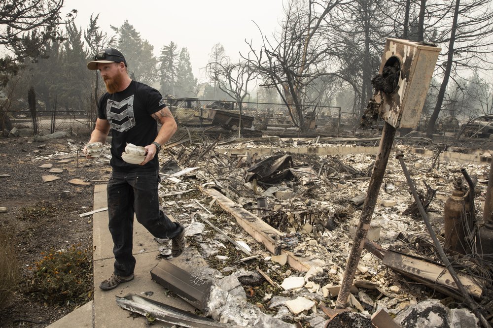 Derek Trenton from Talent, Ore. salvages some items at his parents home as wildfires devastate the region, Friday, Sept. 11, 2020 in Talent, Ore. (AP Photo/Paula Bronstein)