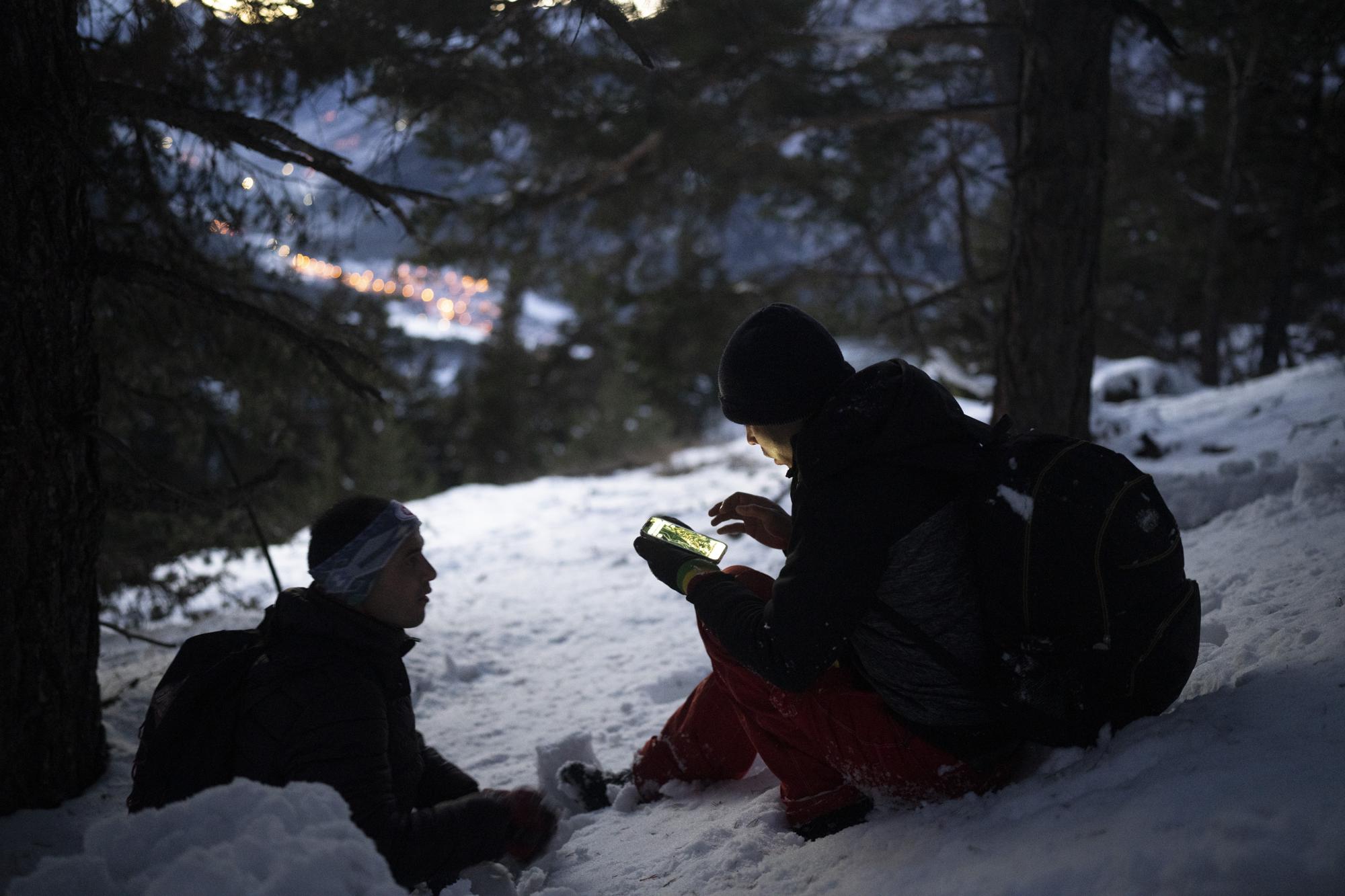 Afghan migrant Ali Rezaie looks at a map on his phone as he and Sayed Hamza trek through the French-Italian Alps to reach a migrant refuge in Briancon, France, Sunday, Dec. 12, 2021. When the Taliban seized power in Afghanistan in August, some Afghans resolved to escape and embarked on forbidding journeys of thousands of kilometers to Europe. Ali Rezaie's odyssey through five countries has carried him high into the French-Italian Alps, where he is pushing through knee-deep snow to evade border guards. (AP Photo/Daniel Cole)