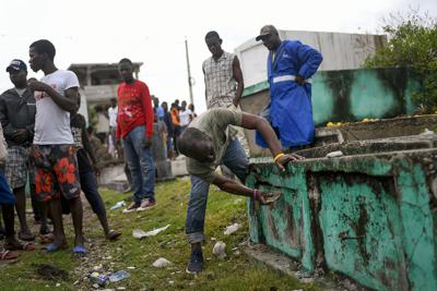 Un trabajador de un cementerio abre una tumba usada para colocar el cadáver de un muchacho que fue hallado la víspera entre los escombros de un edificio derruido en Les Cayes, Haití, el martes 17 de agosto de 2021, tres días después de un sismo de magnitud 7,2. (AP Foto/Matias Delacroix)