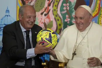 El papa Francisco, acompañado por José María del Corral, presidente de Scholas Occurrentes, sostiene un balón de fútbol que le regalaron en la primera reunión mundial de "Ecociudades Educativas", promovida por Scholas Occurrentes, en el Vaticano, 25 de mayo de 2023. (AP Foto/Andrew Medichini)