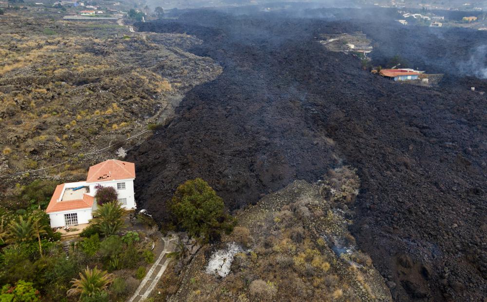 La lava de una erupción volcánica fluye destruyendo casas en la isla de La Palma en Canarias, España, martes 21 de septiembre de 2021. Un volcán inactivo en una pequeña isla española en el Océano Atlántico entró en erupción el domingo, lo que obligó a la evacuación de miles de personas. gente.  Enormes columnas de humo blanco y negro se dispararon desde una cresta volcánica donde los científicos habían estado monitoreando la acumulación de lava fundida debajo de la superficie.  (Foto AP / Emilio Morenatti)