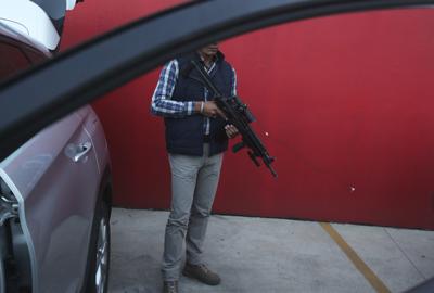 Un guardaespaldas asignado por el gobierno para el candidato a alcalde Guillermo Valencia permanece en guardia el sábado 22 de mayo de 2021 durante una de las escalas de campaña de ese candidato del PRI en Morelia, estado de Michoacán, México. (AP Foto/Marco Ugarte)