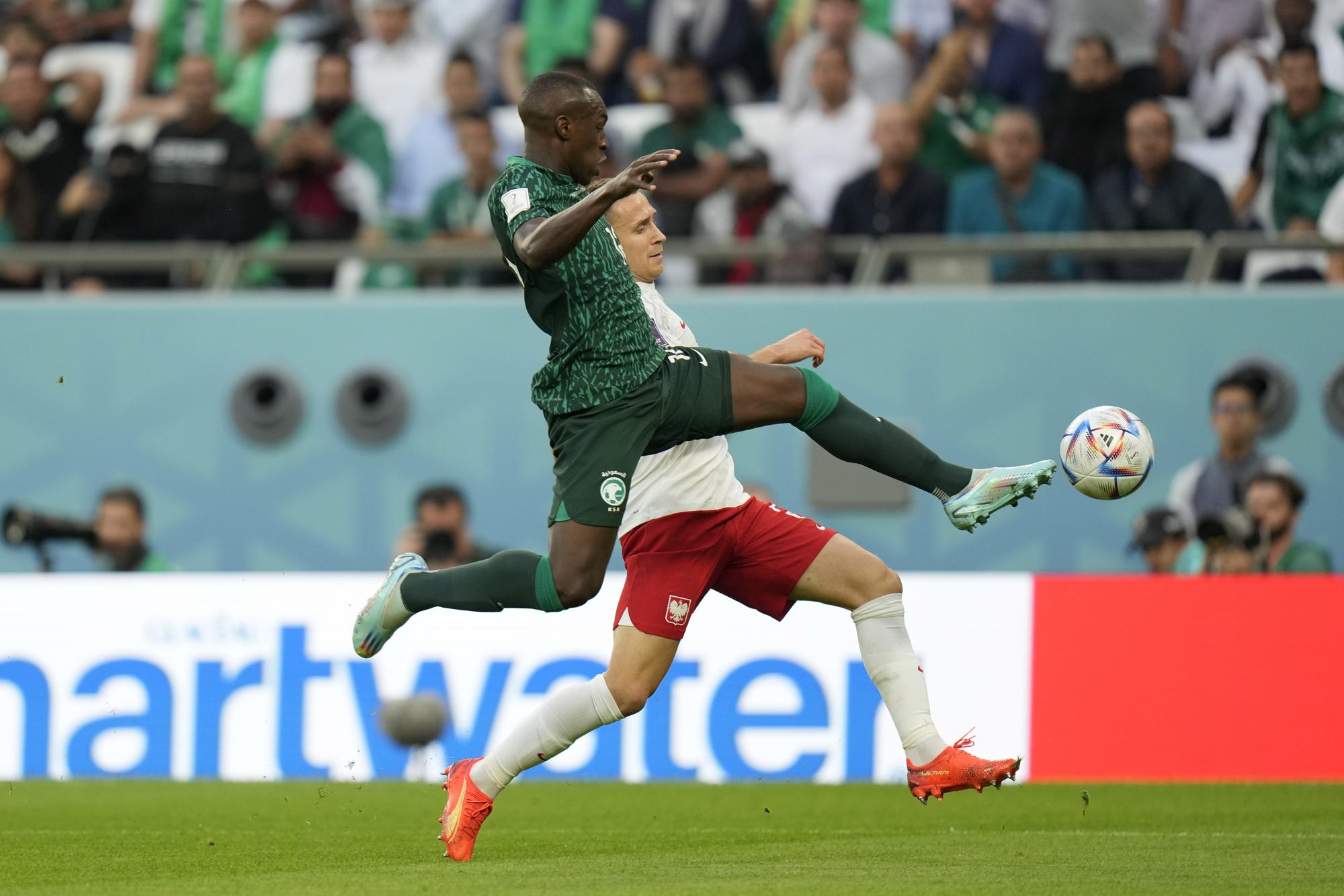 Saudi Arabia's Saud Abdulhamid, foreground, fights for the ball with Poland's Przemyslaw Frankowski during the World Cup group C soccer match between Poland and Saudi Arabia, at the Education City Stadium in Al Rayyan , Qatar, Saturday, Nov. 26, 2022. (AP Photo/Francisco Seco)
