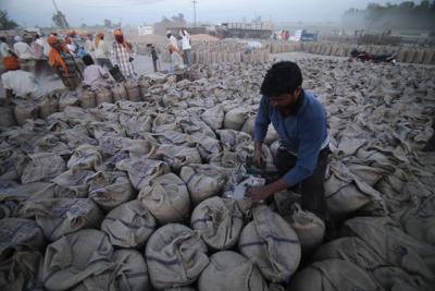 En esta imagen de archivo, un trabajador cierra sacos llenos de trigo en Gurdaspur, en el estado de Punjab, en el norte de India, el 30 de abril de 2014. (AP Foto/Channi Anand, archivo)