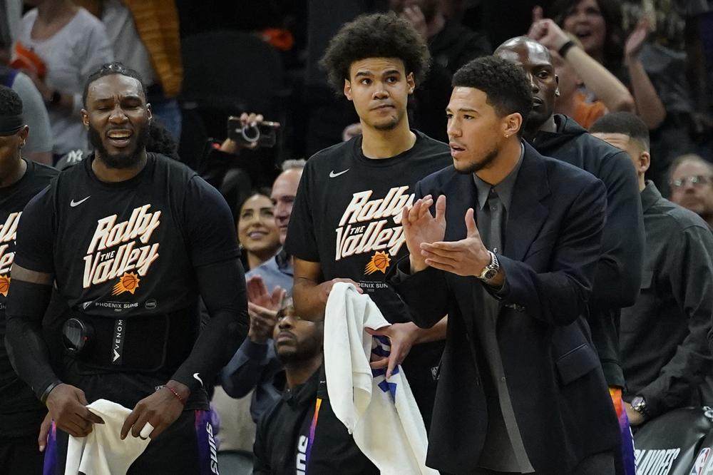 Phoenix Suns guard Devin Booker watches from the bench during the first half of Game 5 of an NBA basketball first-round playoff series against the New Orleans Pelicans, Tuesday, April 26, 2022, in Phoenix. (AP Photo/Matt York)