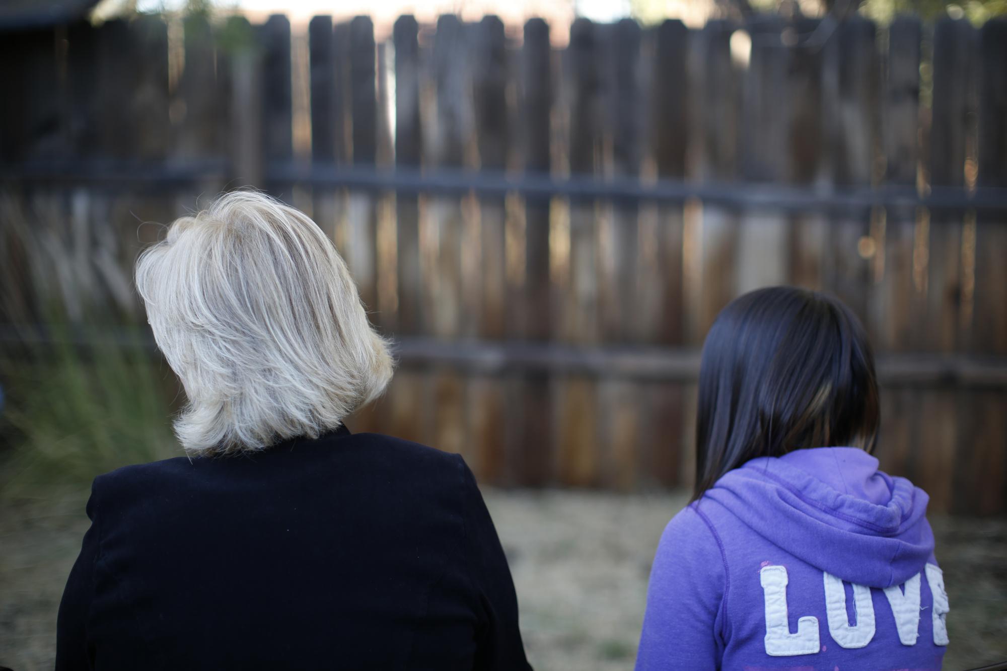 MJ and her adoptive mother sit for an interview with The Associated Press in Sierra Vista, Ariz., Oct. 27, 2021. State authorities placed MJ in foster care after learning that her father, the late Paul Adams, sexually assaulted her and posted video of the assaults on the Internet. (AP Photo/Dario Lopez-Mills)