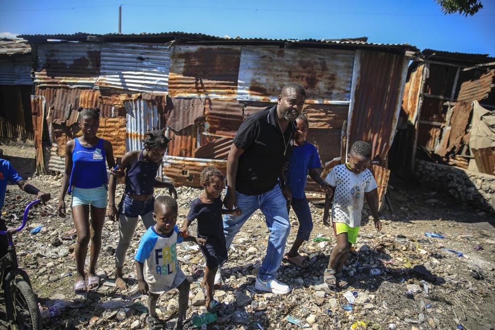 Jimmy Cherizier, the leader of the "G9 et Famille" gang, walks with children as he visits La Saline district of Port-au-Prince, Haiti, Tuesday, Jan. 24, 2023. Internationally, Cherizier is known as Haiti’s most powerful and feared gang leader, sanctioned by the United Nations for “serious human rights abuses,” and the man behind a fuel blockade that brought the Caribbean nation to its knees late 2022. (AP Photo/Odelyn Joseph)