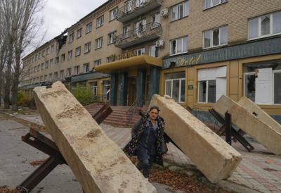 Una mujer camina entre obstáculos antitanques frente a un hotel en Bakhmut, en la región de Donetsk, Ucrania, el viernes 28 de octubre de 2022. (AP Foto/Efrem Lukatsky)