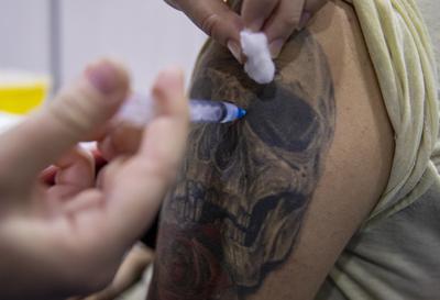 Un trabajador de la salud inyecta a un estudiante una dosis de la vacuna CanSino contra COVID-19 en un sitio de vacunación en el campus de la Universidad Andrés Bello, en Santiago, Chile, el jueves 3 de junio de 2021. (AP Foto/Esteban Felix)