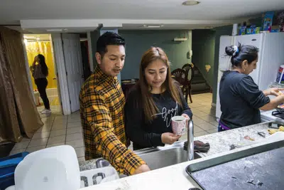 Klever Ortega y su esposa Cristina Lema, ambos migrantes de Ecuador, preparan el desayuno para su familia, el 3 de marzo de 2023, en Spring Valley, Nueva York. (Foto AP/Eduardo Muñoz Alvarez)