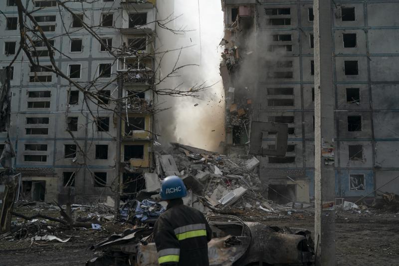 A firefighter looks at a part of a wall falling from the residential building that was heavily damaged after a Russian attack in Zaporizhzhia, Ukraine, Sunday, Oct. 9, 2022. (AP Photo/Leo Correa)