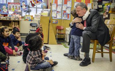 Fotografía de archivo del alcalde de la ciudad de Nueva York Bill de Blasio abrazando a un niño después de leer un libro a un salón de preescolar en P.S. 130 en Nueva York, el martes 25 de febrero de 2014. (AP Foto/Seth Wenig, Archivo)