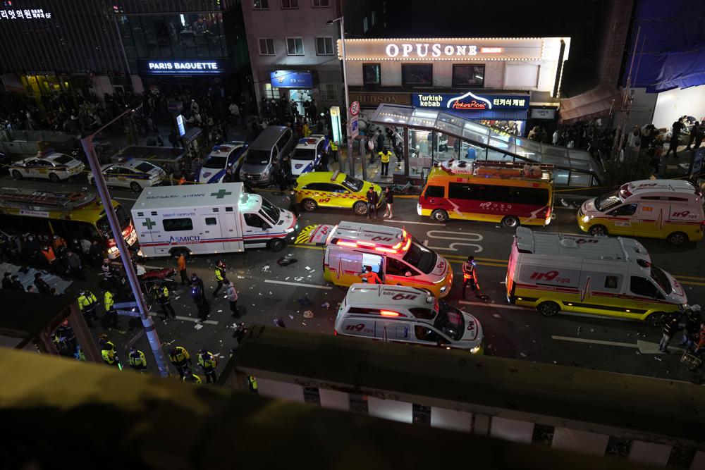 Ambulances and rescue workers gather near the scene in Seoul, South Korea, Sunday, Oct. 30, 2022. At least 120 people were killed and 100 more were injured as they were crushed by a large crowd pushing forward on a narrow street during Halloween festivities in the capital of Seoul, South Korean officials said. (AP Photo/Lee Jin-man)