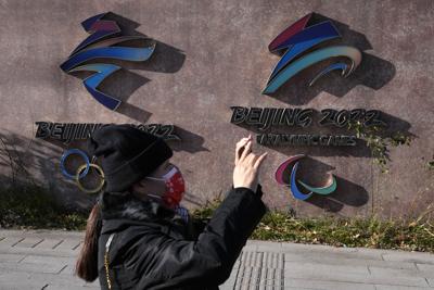 Una mujer con mascarilla hace fotos cerca de los logotipos de los Juegos Olímpicos y Paralímpicos de Invierno de Beijing 2022, en China, el martes 9 de noviembre de 2021. (AP Foto / Ng Han Guan)