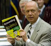 FILE - South Carolina Comptroller General Richard Eckstrom holds up a book he wanted to present to his new Chief of Staff James Holly during his introduction at the Budget and Control Board meeting, Aug. 13, 2009, in Columbia, S.C. Pressure is mounting for Eckstrom after a $3.5B accounting error. (AP Photo/Mary Ann Chastain, File)
