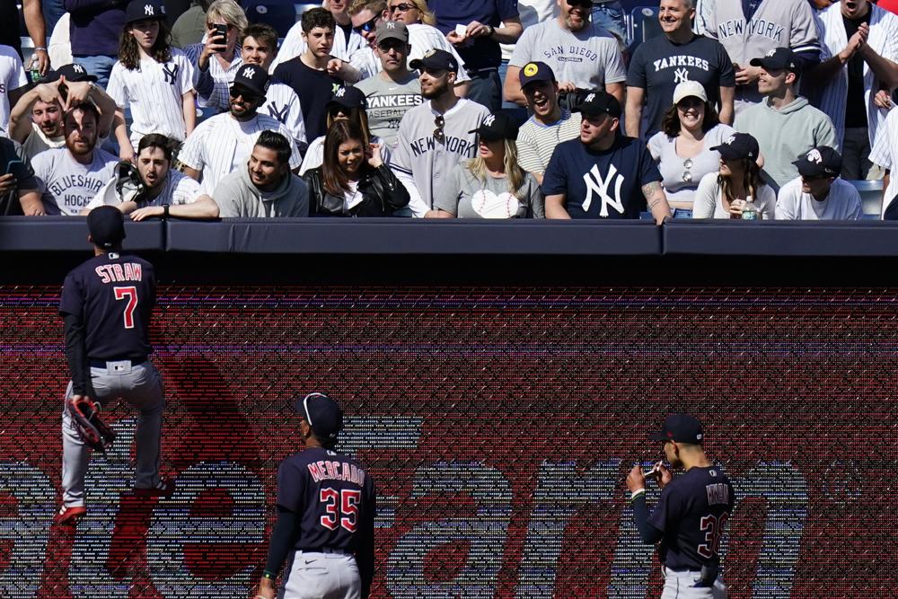 Cleveland Guardians' Myles Straw (7) climbs the left field wall to talk with a fan during the ninth inning of a baseball game against the New York Yankees Saturday, April 23, 2022, in New York. The Yankees won 5-4. (AP Photo/Frank Franklin II)