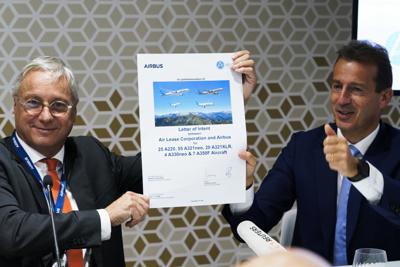 Christian Scherer, izquierda, ejecutivo de Airbus, y el director general de la compañía, Guillaume Faury, posan luego de firmar un documento conmemorativo que marca un acuerdo de venta en el Espectáculo Aéreo de Dubái, Emiratos Árabes Unidos, el lunes 15 de noviembre de 2021. (AP Foto/Jon Gambrell)