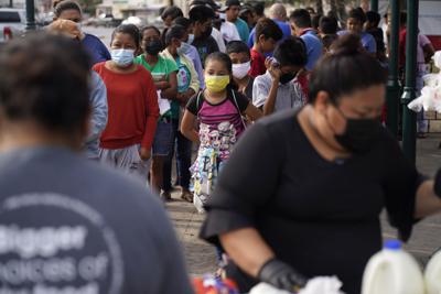 En esta imagen de archivo, varias personas esperan en fila para recibir alimentos donados por una iglesia próxima a un campamento de migrantes, el 14 de mayo de 2021, en Reynosa, México.  El asentamiento, como otros en la frontera norte de México, sirve de alojamiento temporal para los migrantes que buscan solicitar asilo en Estados Unidos.  (AP Foto / Gregory Bull, archivo)