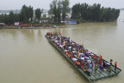 Rescatistas usan una barcaza motorizada para desalojar a residentes de un área rural inundada en Xinxiang, provincia de Henan, China, el viernes 23 de julio de 2021. (Chinatopix vía AP)